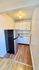 Cozy and efficient kitchen featuring sleek white cabinets, modern refrigerator, and elegant wood flooring.