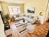 Bright and modern living room with a cozy white sofa, stylish decor, and hardwood floors.