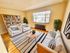 Charming living room with elegant decor, showcasing white furniture, striped cushions, and a cozy ambiance with abundant natural light.