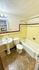 Charming bathroom with vintage yellow and maroon tile design, complete with a bathtub, sink, and toilet, creating a cozy retro atmosphere.
