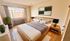 Bright and inviting bedroom with modern decor, featuring a large window, cozy bedding, and stylish wooden furniture.