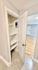 Bright hallway with modern closet featuring white shelves, blending into an inviting living area with hardwood floors.