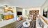 Bright and inviting living space with cozy seating, modern decor, and an adjacent kitchen featuring warm wooden cabinetry.