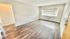 Bright and spacious living room with large window, sleek hardwood flooring, and modern white walls.