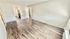 Bright and spacious living area with sleek wood flooring and modern finishes, leading to a cozy kitchen.