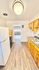 Bright and welcoming kitchen with modern appliances, wooden cabinetry, and sleek countertops, leading to a sunlit living area.