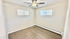 Bright and airy room featuring a ceiling fan, two wide windows, and sleek hardwood flooring.