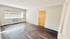 Bright and spacious living room with sleek dark wood flooring, large window for natural lighting, and modern decor possibilities.