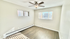 Bright apartment room with elegant hardwood flooring, modern ceiling fan, and large windows offering ample natural light.