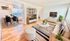 Bright and inviting living room with modern decor, featuring a cozy sitting area, striped rug, and adjacent dining space with natural light.