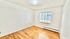 Bright, spacious room with natural light, white brick walls, and sleek hardwood flooring.