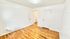 Bright empty room featuring hardwood floors, fresh white walls, and natural light streaming through blinds.