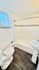 Bright, modern bathroom featuring a pristine bathtub, elegant pedestal sink, and stylish white tiled walls.