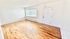 Bright and airy apartment interior with sleek hardwood floors, large window for natural light, and modern white walls.