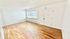 Bright and airy living room with polished wooden floors, large window, and sleek white walls for a modern touch.