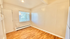 Bright, inviting room with hardwood floors and natural light from a large window, perfect for a cozy living space.
