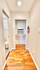 Bright hallway with elegant hardwood floors, featuring a built-in air conditioning unit and a glimpse of a modern bathroom.