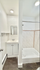 Bright and modern bathroom with sleek white tiles, elegant vanity, and spacious shower tub.