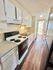 Charming galley kitchen with white cabinetry, sleek countertops, and modern appliances on warm wood flooring.