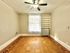 Bright and inviting room featuring elegant parquet flooring, a ceiling fan, and large window with natural light.