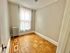 Charming room with elegant hardwood floors and a bright window draped with sheer curtains, perfect for cozy living.