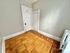 Elegant room featuring intricate parquet flooring, classic white door, and light gray walls.