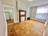 Charming room with elegant parquet flooring, classic fireplace, and ample natural light flowing through sheer-curtained windows next to a cozy kitchen space.