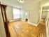 Bright and inviting hallway with elegant wood flooring, leading to a cozy bathroom and charming stairs.