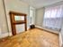 Charming room with elegant wooden fireplace, large window with sheer curtains, and classic parquet flooring.