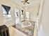 Bright living area with elegant rug, ceiling fan, and natural light from multiple windows, showcasing a spacious layout.