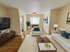 Elegant living room with modern decor, featuring cozy white sofas, a sleek wooden coffee table, and a large flat-screen TV for a luxurious atmosphere.