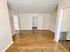Inviting living space with warm hardwood floors and ample natural light, leading to adjacent rooms.