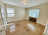 Bright and airy room with polished hardwood floors and large windows letting in natural light, perfect for a cozy home atmosphere.
