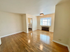 Bright and inviting living area with gleaming hardwood floors and a large window, seamlessly leading to a cozy kitchen space.