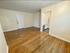Charming living space with elegant hardwood flooring and a glimpse into the cozy adjoining kitchen area.