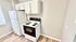 Bright and modern kitchen featuring a sleek white fridge and stove, complemented by elegant cabinetry and stylish flooring.