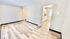 Bright, modern living space with sleek wood flooring and an open view into a contemporary kitchen.