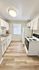 Bright, modern kitchen with sleek white cabinetry, elegant countertops, and wood-style flooring.