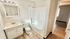 Contemporary bathroom design with elegant vanity, pristine bathtub, and warm wood flooring, leading to cozy bedroom space.