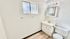 Bright, modern bathroom featuring sleek fixtures, a large mirror with lighting, and a stylish frosted window.