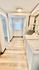 Bright and inviting laundry area with modern washer and dryer, well-lit hallway, and stylish wood flooring.