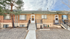 Charming brick townhome with quaint front entrance, cozy windows, and welcoming steps surrounded by natural landscape.