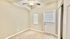 Bright bedroom with soft carpet, dual windows, and ceiling fan, providing comfort and style.