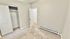 Bright bedroom with soft carpet, open closet, and neutral walls, offering a cozy and inviting atmosphere.