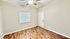 Inviting room with elegant hardwood flooring, a ceiling fan, and ample natural light through the window.
