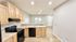 Inviting kitchen with warm wood cabinetry, black appliances, and open layout leading to bright living area.