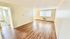 Bright and spacious living room with sleek wooden flooring and large windows, offering ample natural light.