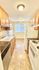 Bright and inviting galley kitchen with modern appliances, wooden cabinetry, and elegant stone countertops, featuring a large window with a peaceful view.