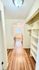 Charming hallway with elegant wooden flooring leading to a bright, spacious kitchen featuring modern appliances and ample shelving.