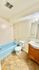 Bright, clean bathroom featuring a stylish blue bathtub, modern vanity, and elegant tile flooring.